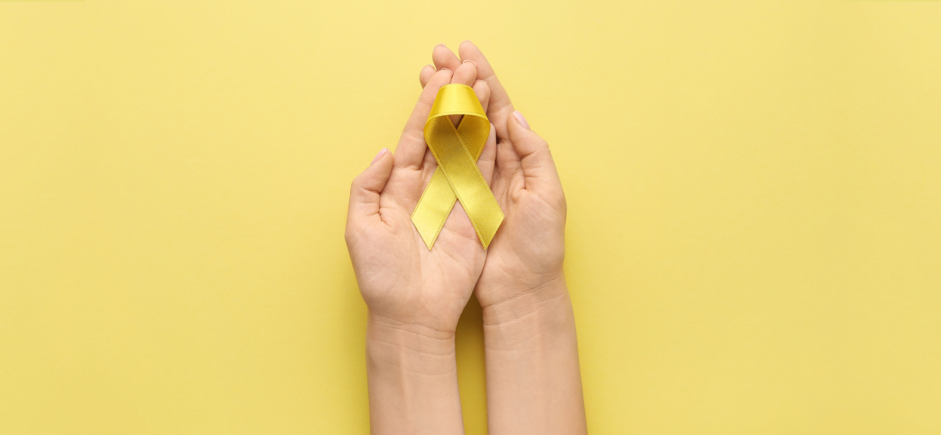 Hands with Golden Awareness Ribbon on Yellow Background. Cancer Concept